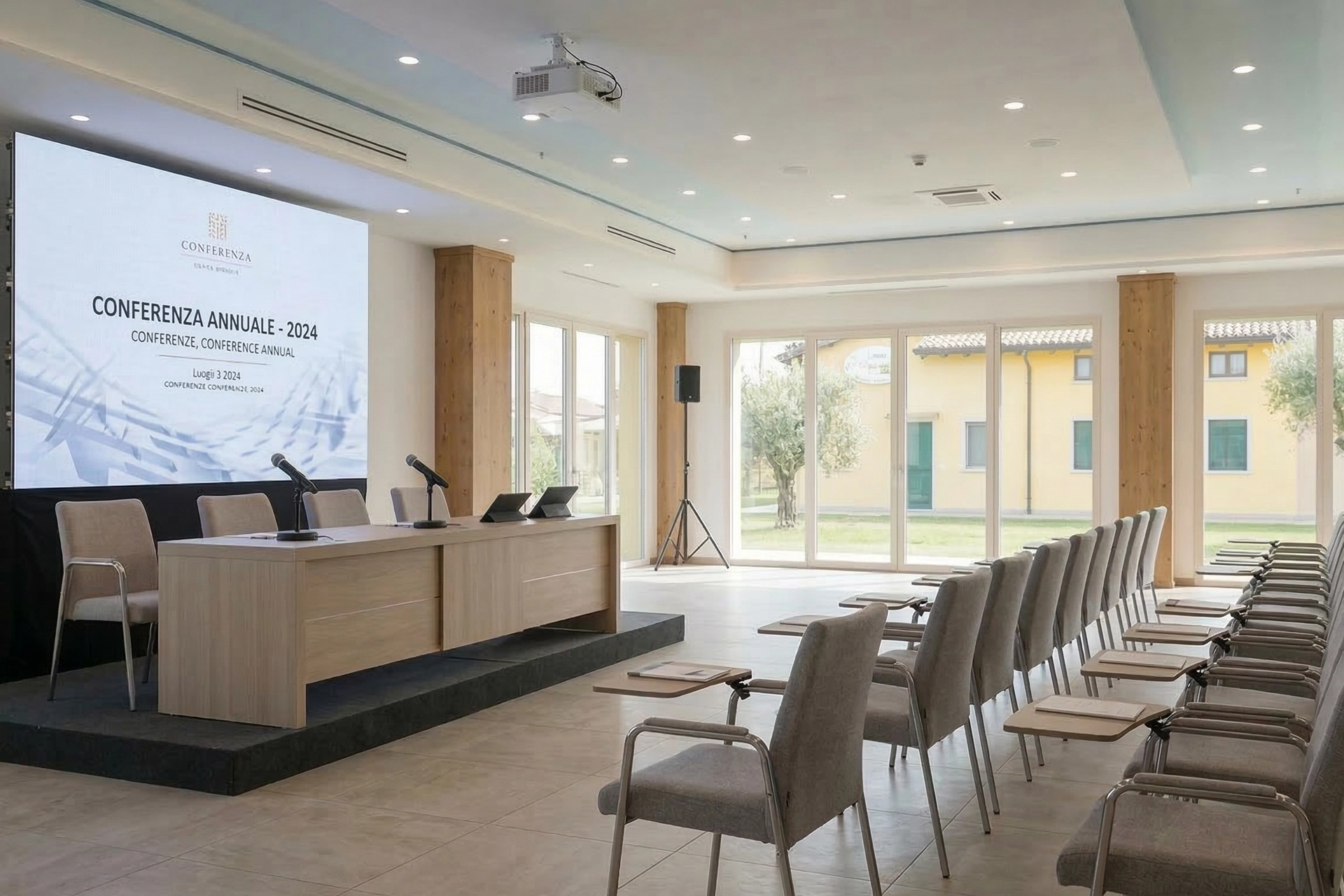 Dettaglio ravvicinato sul tavolo relatori con podio in legno, due microfoni e un laptop. Sala metting tenuta elisabetta